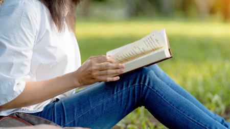 Young Woman  Enjoying a Book Reading Outdoors. Focus book.