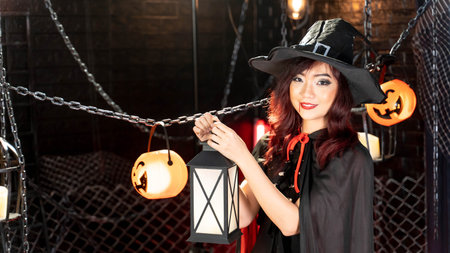 Happy halloween day. Portrait Asian woman in halloween costume witch black hat carrying lantern.の写真素材