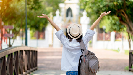 traveler vacation fun summer woman dancing in freedom with arms up happy. Carefree girl tourist in temple destination wearing white shirt and hat.の写真素材