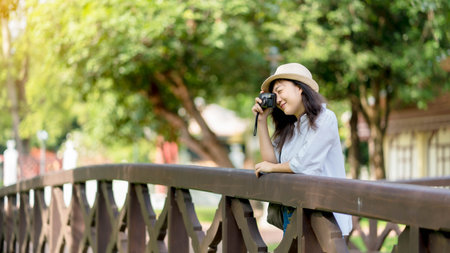 Tourist traveler photographer making pictures river scape on photo camera on background bridge, hipster girl enjoying peak nature holidayの写真素材