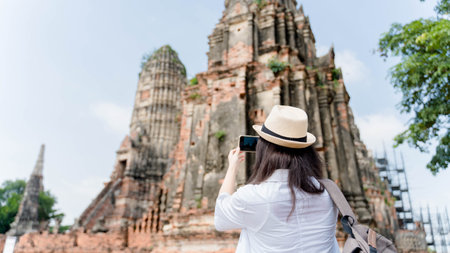 Young asian woman taking photo on his mobile phone camera of a beautiful landscape while standing...