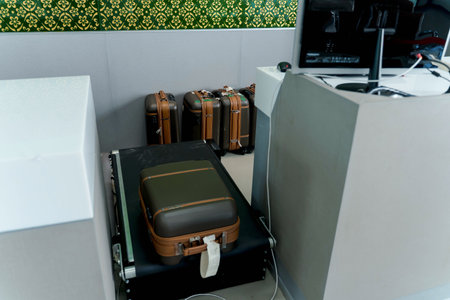 Suitcases lined up at baggage screening area in an airport security checkpoint, close-up view of luggage on conveyor belt in travel inspection zoneの写真素材