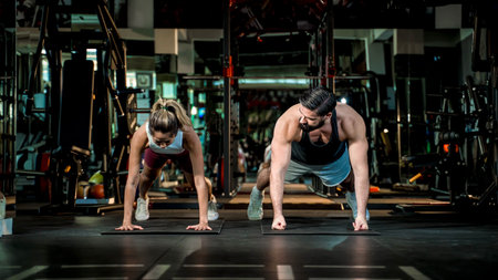 Man and woman doing synchronized push-up exercise in modern gym, showcasing teamwork, core strength, and high-intensity partner workout in fitness training session.の写真素材