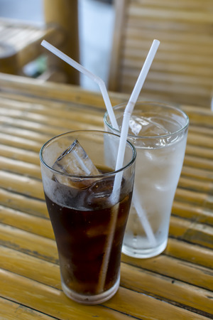glass of cola with ice on wooden tableの写真素材