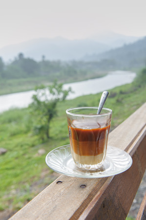 Cup of hot tea and croissant on balcony with mountains behindの写真素材