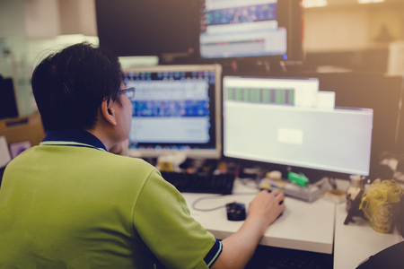 Software engineering or computer programming or Developing new approaches. Close-up of young businessman looking at many monitor while sitting at the desk in creative or development office. Software engineering or computer programming or Developing new approaches. Close-up of young businessman looking at many monitor while sitting at the desk in creative or development office.