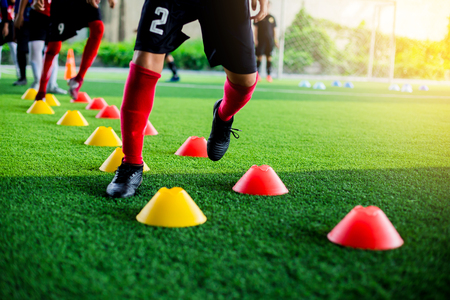 Kid soccer players Jogging and jump between cone marker for football training.の写真素材