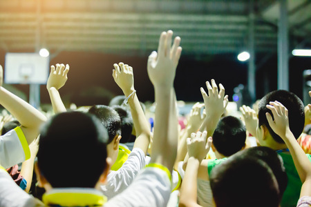 Selective focus to Asian boy hands up or raised hands to vote for democratic in meeting hall.の写真素材