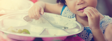 Cute asian kid boy eating foods by self. Child holding a spoon. Selective focus. Copy space. Kid enjoy eating.の写真素材