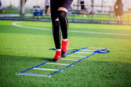 Young boy soccer players Jogging and jump between ladder drills for football training. Ladder drills exercises for football or soccer team. Kid soccer player exercises on ladder drills.の写真素材