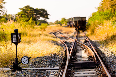 Railroad switch with train in the morning sun. The conception of  change or choices or decide. Trees and grass, yellow sunlight. Railway junction. Heavy industry. Railways.Thailand.の写真素材