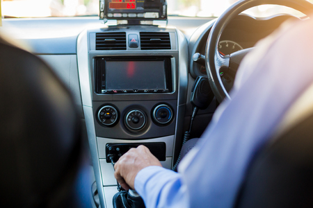 Selective focus of man driving and change gear a car. View from inside the taxi car with radio communication.の写真素材