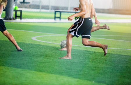 Soccer players not wearing a sport shirt and barefoot do trap and control the ball for shoot to goal. Soccer players fighting each other by kicking the ball.の写真素材