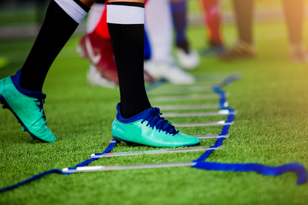 Young boy soccer players Jogging and jump between ladder drills for football training. Ladder drills exercises for football or soccer team. Kid soccer player exercises on ladder drills.の写真素材