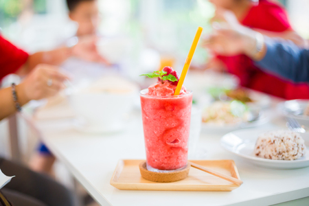 Juice Strawberry shake on the white table in restaurant with blurry women and children are eating foodの写真素材