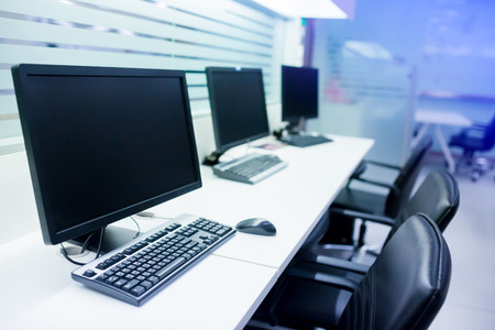 composite image of computer in office or training room. the computer is on the table in a bright interior. white desk and black revolving chair with computer pc and mouse in office.の写真素材