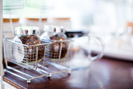 coffee bean and tea with sugar in a glass jar on wooden table in cafe