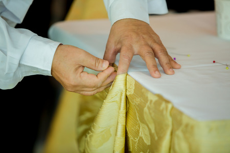 Hands of staff preparing the tablecloth with pin and decorations for guestsの写真素材