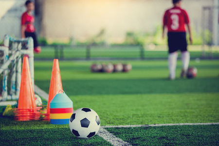 soccer ball and soccer training equipment on green artificial turf with blurry of soccer players training. Soccer Academy.の写真素材