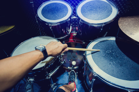man playing the drum set with wooden drumsticks in music room , the concept of musical instrumentの写真素材