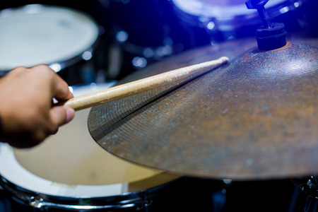man playing the drum set with wooden drumsticks in music room , the concept of musical instrumentの写真素材