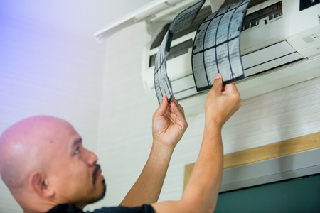 selective focus to left hand of male technician cleaning air conditioner indoors with a lot of dust. Basic cleaning dust in air conditioner at home with yourself.の写真素材