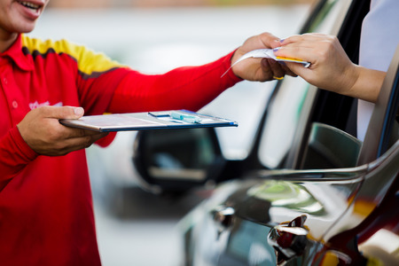 Selective focus to woman driver pay credit card with staff for fuel in gas station.の写真素材