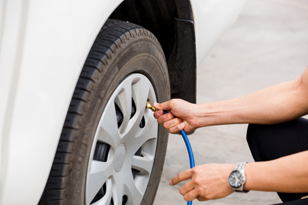 driver checking air pressure and filling air in the tires close up, safety before travelの写真素材