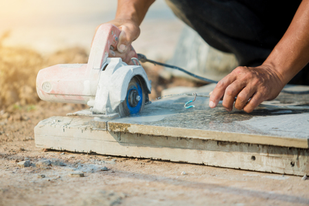 worker cutting granite stone with an diamond electric saw blade and use water to prevent dust and heat at a construction siteの写真素材