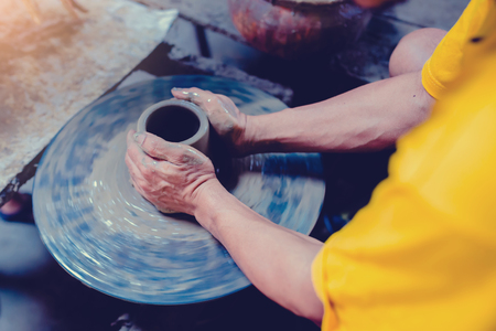 pottery, workshop, ceramics art concept - closeup on male hands sculpt new utensil with a tools and water, man's fingers work with potter wheel and raw fireclay, at Ko Kret, Thailandの写真素材