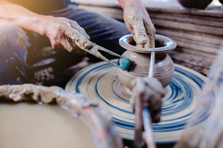 pottery, workshop, ceramics art concept - closeup on male hands sculpt new utensil with a tools and water, man's fingers work with potter wheel and raw fireclay, at Ko Kret, Thailandの写真素材