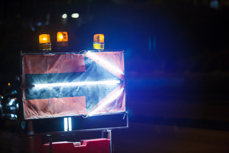 fluorescent light display arrow at under construction road.の写真素材