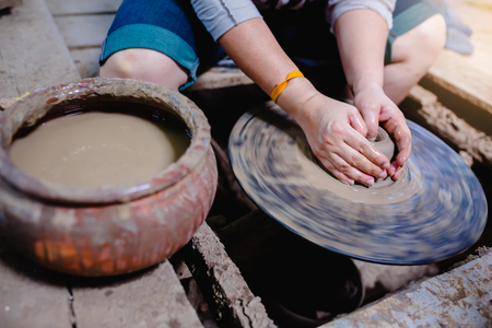 Woman moulding clay on pottery wheel. Craftswoman making pot in workshop.の写真素材