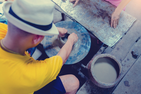 pottery, workshop, ceramics art concept - closeup on male hands sculpt new utensil with a tools and water, man's fingers work with potter wheel and raw fireclay, at Ko Kret, Thailandの写真素材