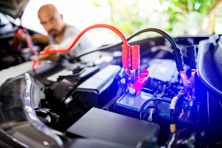blurry of male mechanic changing car battery, mechanic engineer fixing car battery with delivery service on road or home, the concepts of car maintenance services in every locationの写真素材