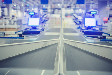 blurry image of product conveyor and computer with cashier machine at the pay counter in the...
