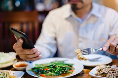 man is eating along with playing smartphone. Lifestyle in today's society. man relaxing having  in...