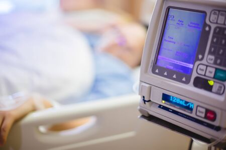 Selective focus to Infusion pumps with blurry patient in hospital. blurry female patients lying in the nursing bed.の写真素材