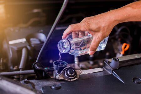 hands of mechanic check water in car radiator and add water to car radiator, service and maintenance...