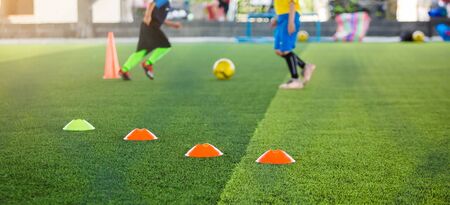 selective focus to marker cones are soccer training equipment on green artificial turf with blurry...