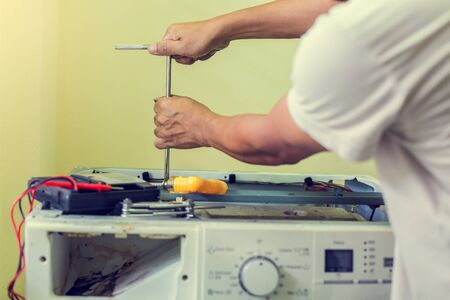 Car mechanic is holding a wrench ready to check the engine and maintenance with blurry voltmeter for...