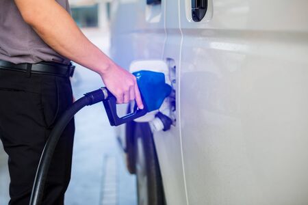 Hand refilling the white van with fuel at the gas station. Oil and gas energy.