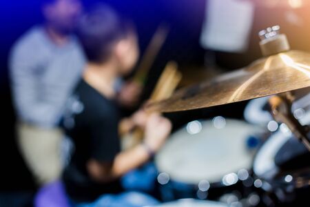 Selective focus to cymbals of drum set with blurry kid learning and play drum set with teacher in music room. The concept of musical instrument.の写真素材