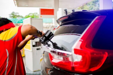Selcective focus to staff using squeegee to clean the Rear window car. Car service in gas station.の写真素材