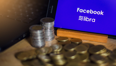 BANGKOK, THAILAND, JULY 23, 2019 : Facebook and Libra text display on smartphone with gold silver coin and laptop background. The concept of business information on technology.のeditorial素材