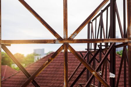 Rust on the steel frame of old advertising billboard with blurry house roof.の写真素材