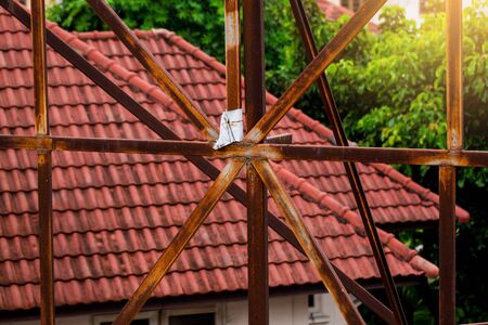 Rust on the steel frame of old advertising billboard with blurry house roof.の写真素材