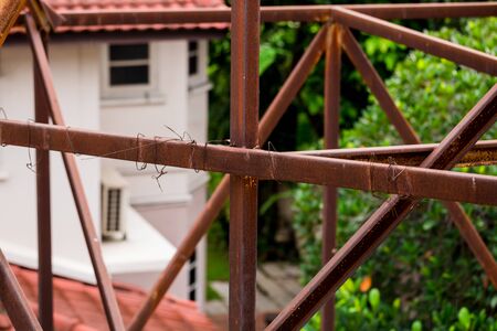Rust on the steel frame of old advertising billboard with blurry house roof.の写真素材