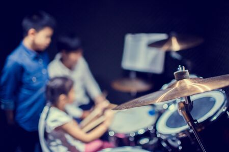 Selective focus to cymbals of drum set with blurry kid learning and play drum set with teacher in music room. The concept of musical instrument.の写真素材