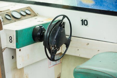 Old and damage steering wheel and dashboard of white speedboat. Damaged speedboat is parking on the river. White speedboat damaged.の写真素材